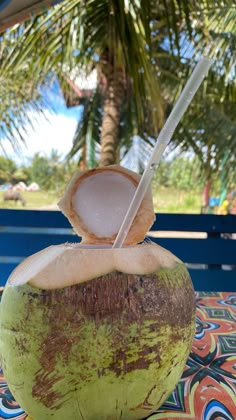 a close up of a coconut drink on a table with a palm tree in the background