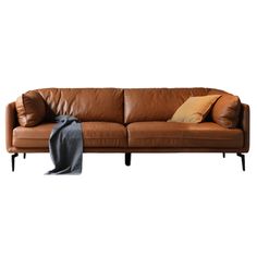 a brown leather couch with two pillows on the armrests and a blanket draped over it