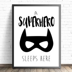 a black and white poster with the words superhero sleeps here on it, against a brick wall