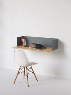 a desk with a chair and computer on it in front of a wall mounted shelf