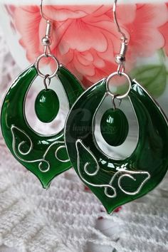 pair of green and white glass earrings with swirl design on the front, hanging from silver earwires