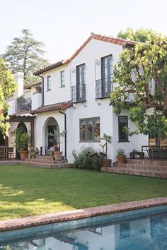 a large white house with a pool in the front yard and trees on either side