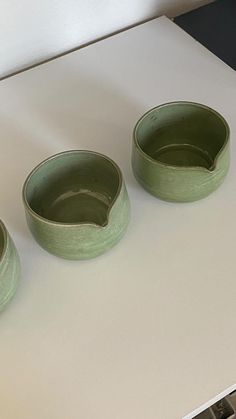 three green bowls sitting on top of a white counter