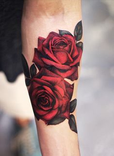 a close up of a person's leg with red roses on the thigh and arm