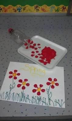 a child's handprint with flowers on it next to a water bottle