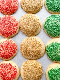 many cookies with sprinkles are lined up on a baking sheet