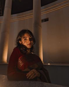 a woman sitting in front of some tall pillars