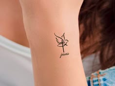 a woman's arm with a small tattoo on it that says jesus in cursive writing