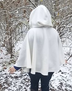 This short white cloak is delightfully soft and comfortable. It's long enough to reach the back of the hand, keeping you warm but keeping your hands available when needed. It has a full hood and closes with a matching cloth frog clasp. This cloak is great for a costume piece or a cozy jacket, great for Spring, Fall, and looks lovely over casual clothes or keeping you warm at a winter wedding. Your cloak will measure about 30 inches in length. This listing is in cream white, but other colors are White Winter Poncho Cape, White Long Sleeve Cape For Fall, White Cloak, Cape With Hood, Clothing Templates, Black Cape, Cozy Jacket, White Fleece, Hooded Poncho