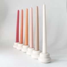 five candles lined up in different colors on a white background