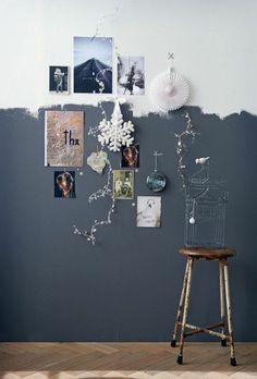 a chair sitting in front of a wall with pictures hanging on the wall and a birdcage next to it