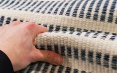 a person's hand is on the edge of a blue and white striped blanket