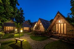 the cottages are lit up at night with lights on and trees in the foreground