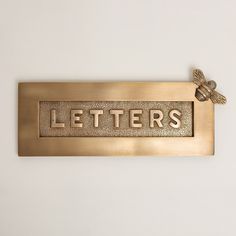 a brass metal sign that says letters with a bee on the front and bottom part