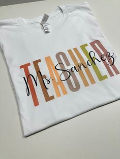 Show your appreciation for your favorite teacher with our Personalized Teacher Shirt! This custom tee makes the perfect gift for new teachers or as a thank you to your mentor. Celebrate their dedication with this unique and thoughtful Teacher Appreciation Gift. How to order 1-pick size and shirt color 2- Add to cart 3- go to cart and in the instructional box enter the custom name Example: Mrs Hernandez 4-Checkout T-shirt .unisex .eco friendly . regular size . soft & comfy Teacher Shirt With Name, Personalised T-shirt, Name Shirt Ideas, Dtf Shirt Ideas, Teacher T Shirt Outfits, Teacher Cricut Shirts, Tshirt Ideas For Teachers, Teacher Vinyl Shirts, Cricut Projects For Teachers