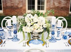 the table is set with blue and white plates, silverware, and floral centerpieces