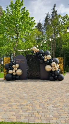 a sculpture made out of black and gold balloons in the middle of a brick walkway