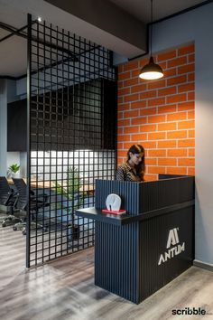 a woman standing at a podium in front of a brick wall with an atm logo on it