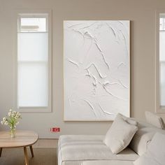 a living room with white furniture and paintings on the wall above it's coffee table