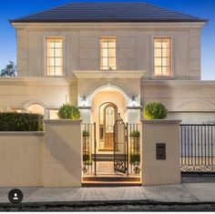 a large white house with an iron gate in the front yard and entrance to it