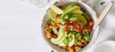 a bowl filled with rice and avocado on top of a white table cloth