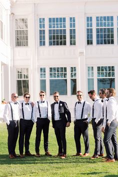 a group of men standing next to each other in front of a large white building