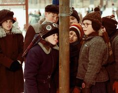 a group of people standing next to each other near a pole in the snow on a snowy day