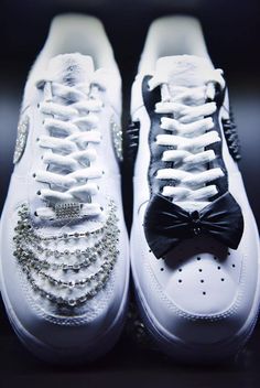 a pair of white sneakers with black and silver bows on them, all adorned with crystals