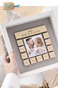 a person holding up a wooden frame with an image of a baby's first year