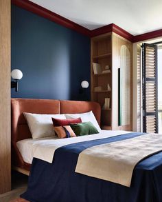 a bedroom with blue walls and a bed that has two pillows on top of it