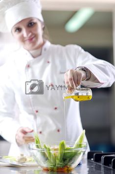 a female chef is pouring olive oil into a glass bowl with green beans in it