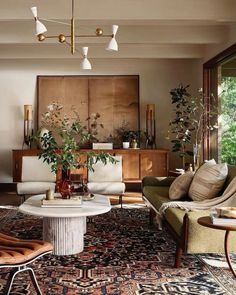 a living room filled with furniture and lots of plants on top of a rug in front of a window