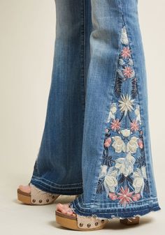 two people standing next to each other wearing jeans with flowers on the bottom and side