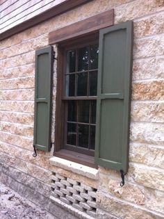 an old brick building with green shutters and wood trimming on the window sill