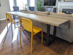 a living room filled with furniture and a fire place next to a table covered in yellow chairs