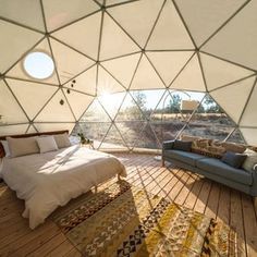 a bed sitting inside of a tent on top of a wooden floor next to a couch