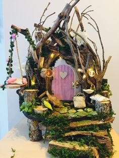 a small fairy house made out of branches and logs with lights on the front door