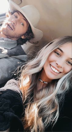 a man and woman sitting in the back seat of a car smiling at the camera