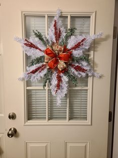 a christmas wreath on the front door of a house decorated with red and white decorations