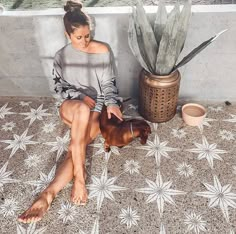 a woman sitting on the ground petting a dog