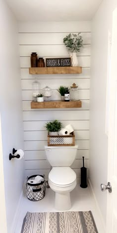 a white toilet sitting in a bathroom next to two shelves filled with plants and other items