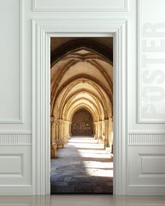 an open door leading to a hallway with white walls and arches on either side, in front of a doorway that leads into another room