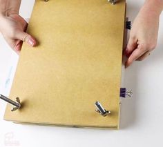 a person holding a clipboard with several clips attached to it and two hands on the clipboard