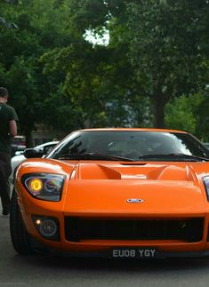 an orange sports car is parked on the street