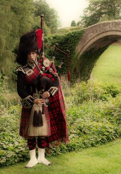 a man in a kilt is holding a bagpipe and posing for the camera