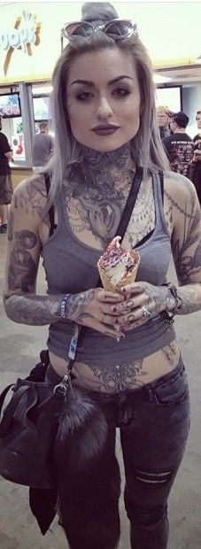 a woman with tattoos and piercings holding an ice cream cone in her right hand