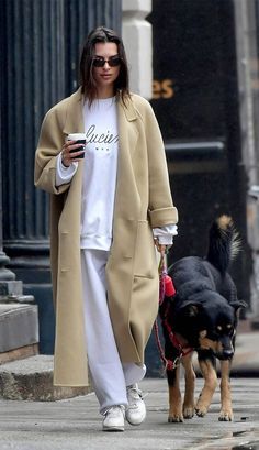 a woman walking her dog while holding a coffee cup