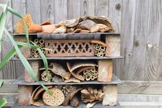 a stack of clay pots sitting on top of a wooden shelf next to a plant