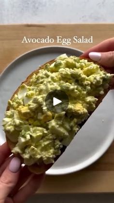 a person is holding up a piece of bread with eggs on it and the words avocado egg salad in front of them