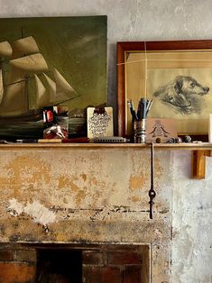 an old fireplace with a painting on the mantle next to it and other art work